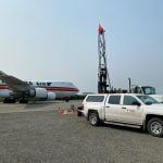 Photo of plane on runway, CRW truck, and drilling equipment